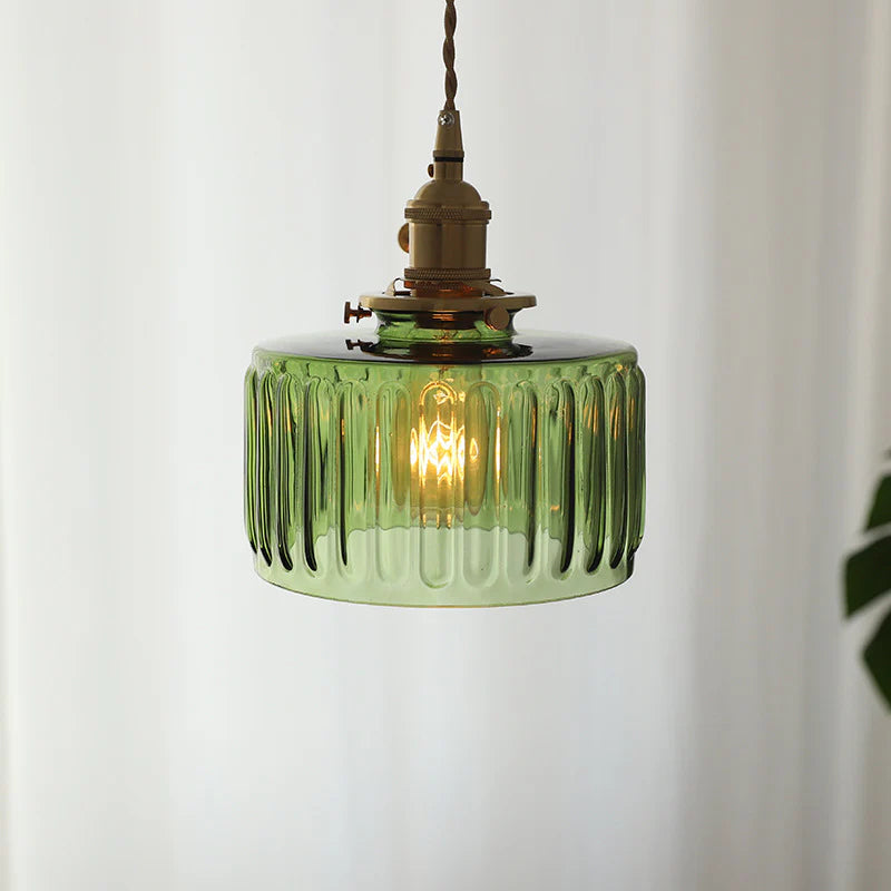 Green glass pendant light with brass fitting on a white background
