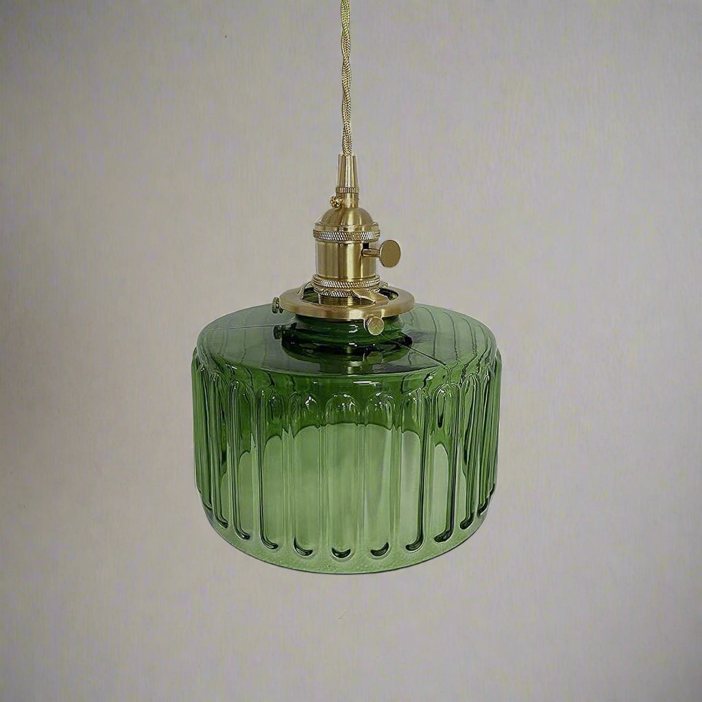 Green glass pendant light with brass fitting on a gray background