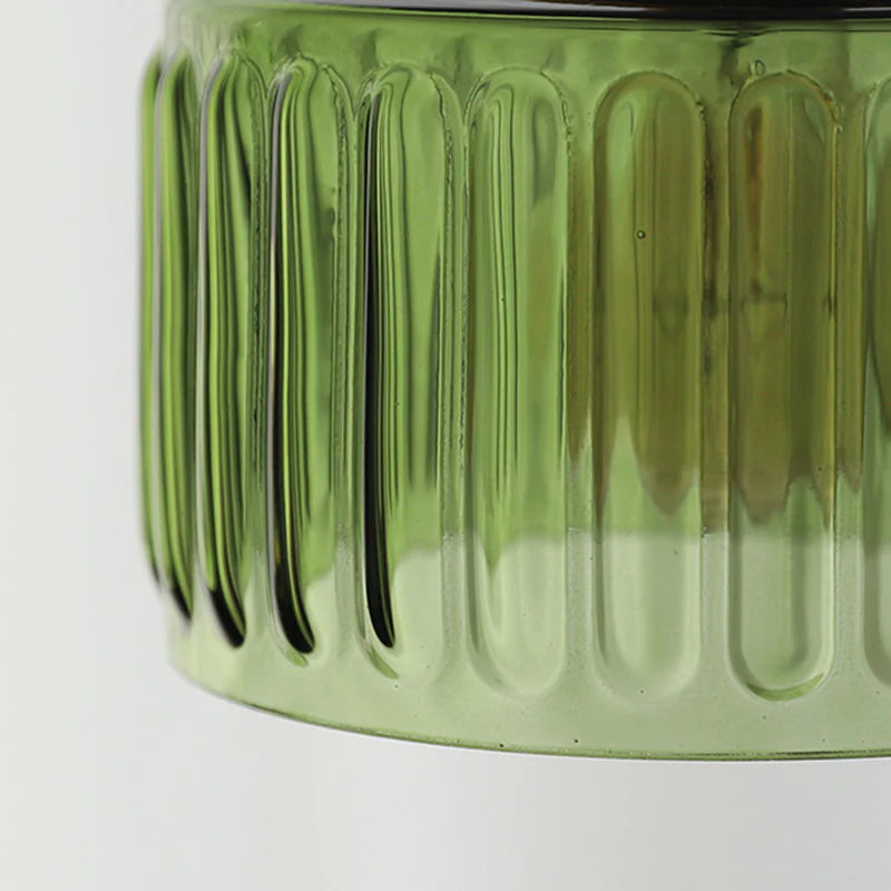 Close-up of a green glass jar with ribbed texture on a white background