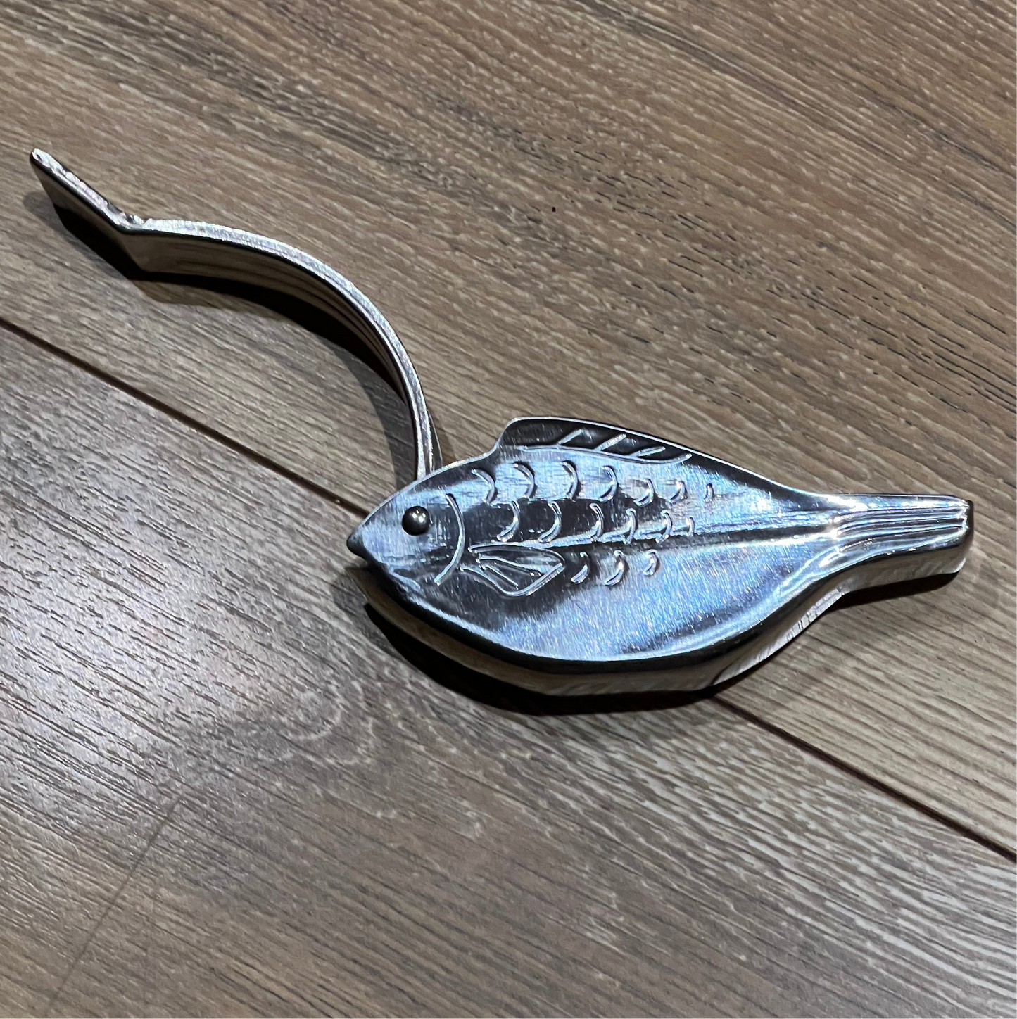 Metallic fish-shaped object on a wooden surface