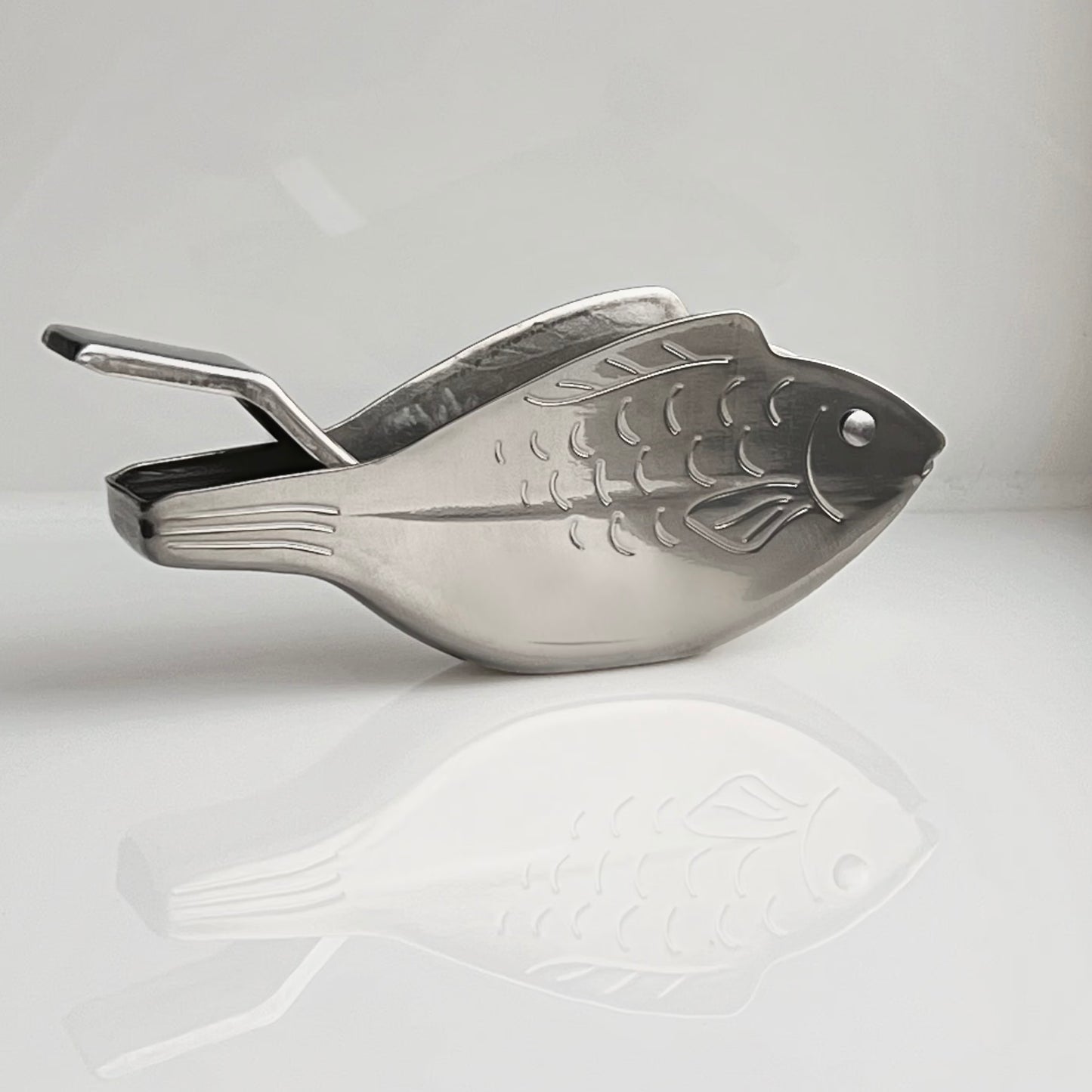 Metallic fish-shaped scoop on a light gray background