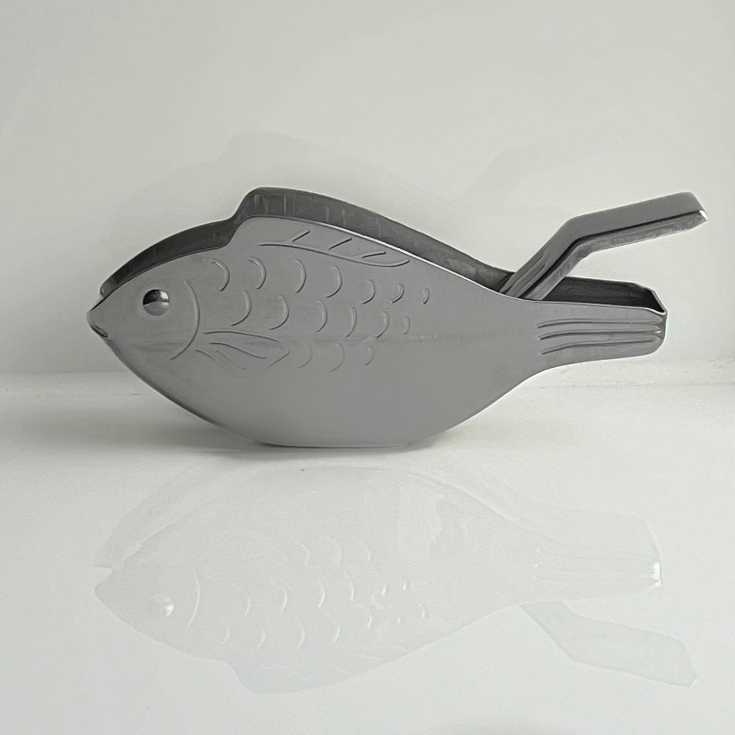 Gray fish-shaped tool on a light gray background