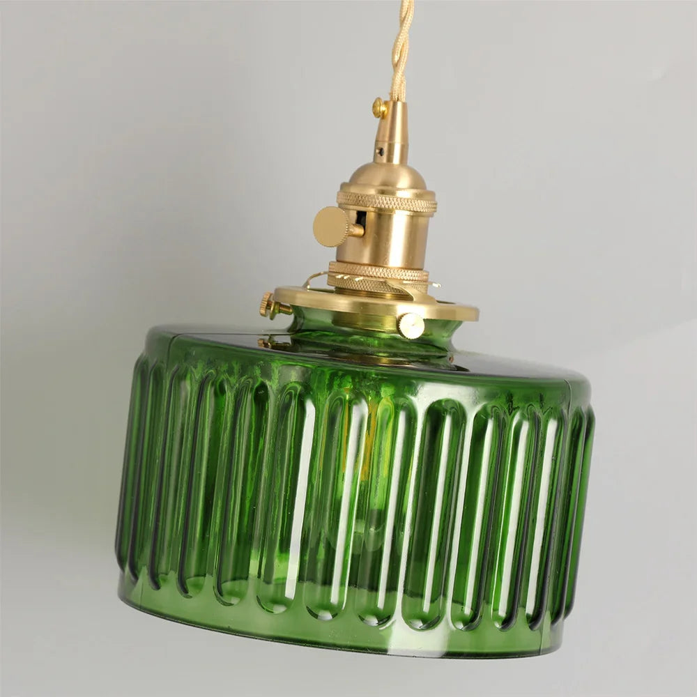 Green glass pendant light with brass fitting on a gray background