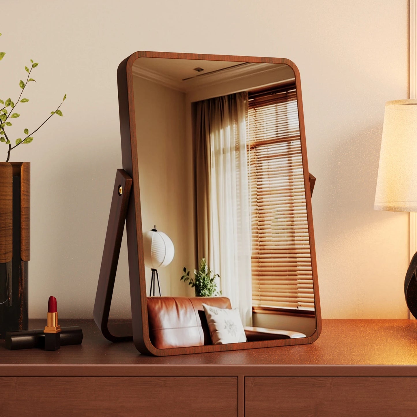 Wooden vanity mirror on a dresser with a lamp and plant in the background