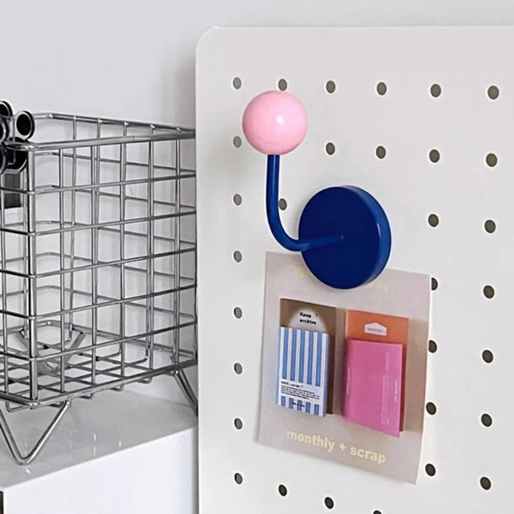 Blue and pink hook on a pegboard with a metal basket and product packaging in the background.