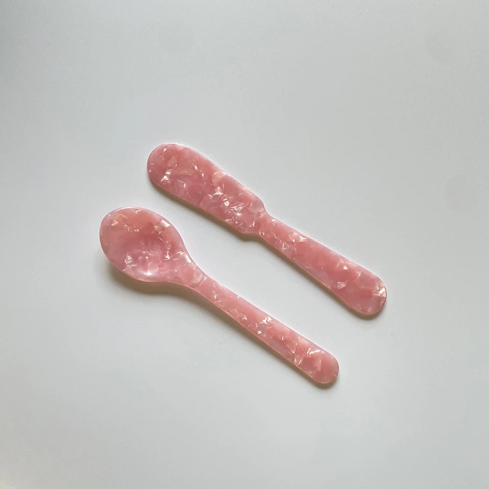 Two pink plastic spoons on a light gray background