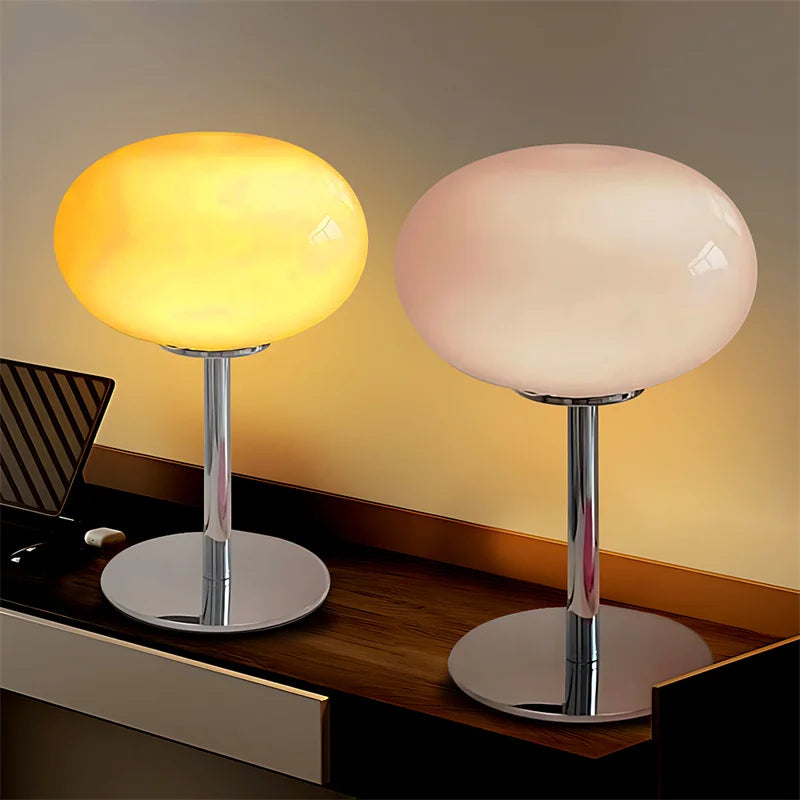 Two table lamps with different colored glass shades on a wooden surface.