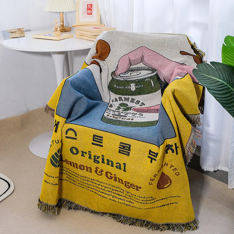 Blanket with a design of a can and text, draped over a chair in a room.