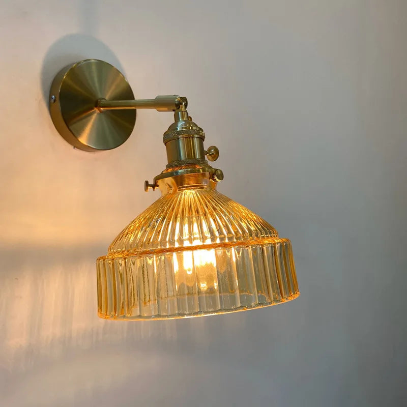 Gold wall sconce with ribbed glass shade on a white wall