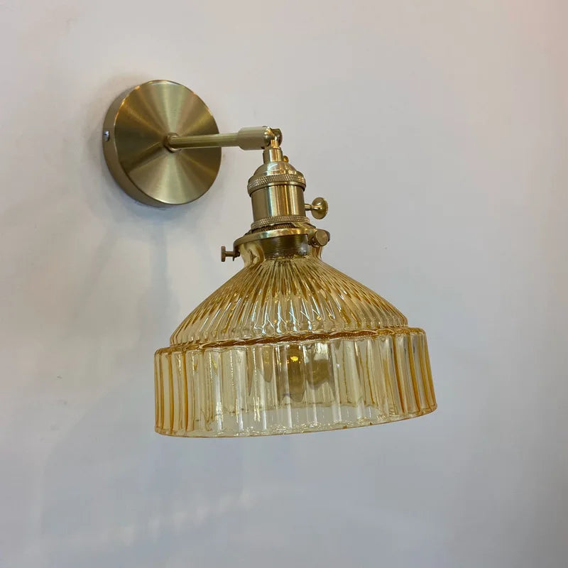 Gold wall-mounted lamp with ribbed glass shade on a white background