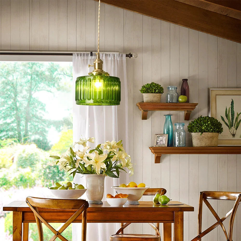 Dining room with wooden table, chairs, and a green pendant light.