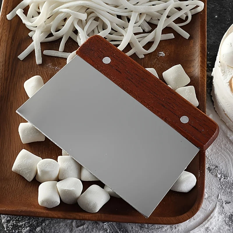 Small cleaver on a wooden cutting board with marshmallows and noodles.
