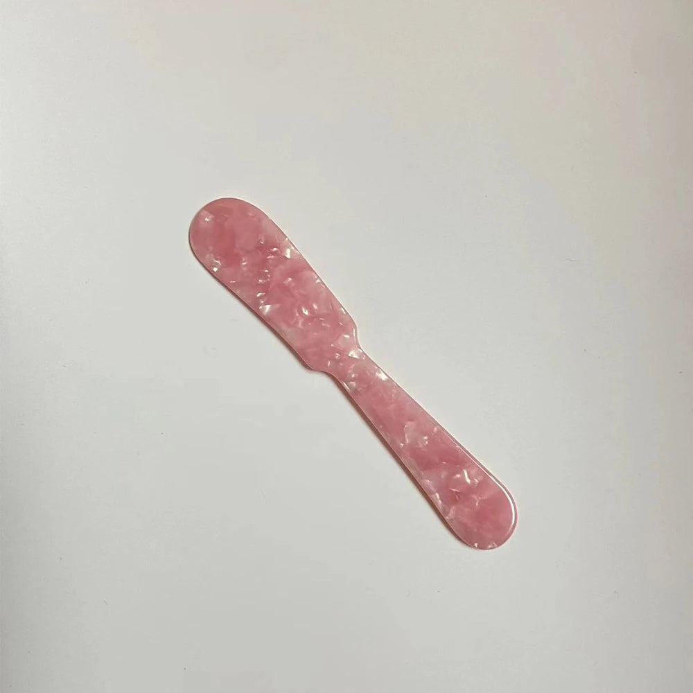 Pink plastic knife on a light gray background