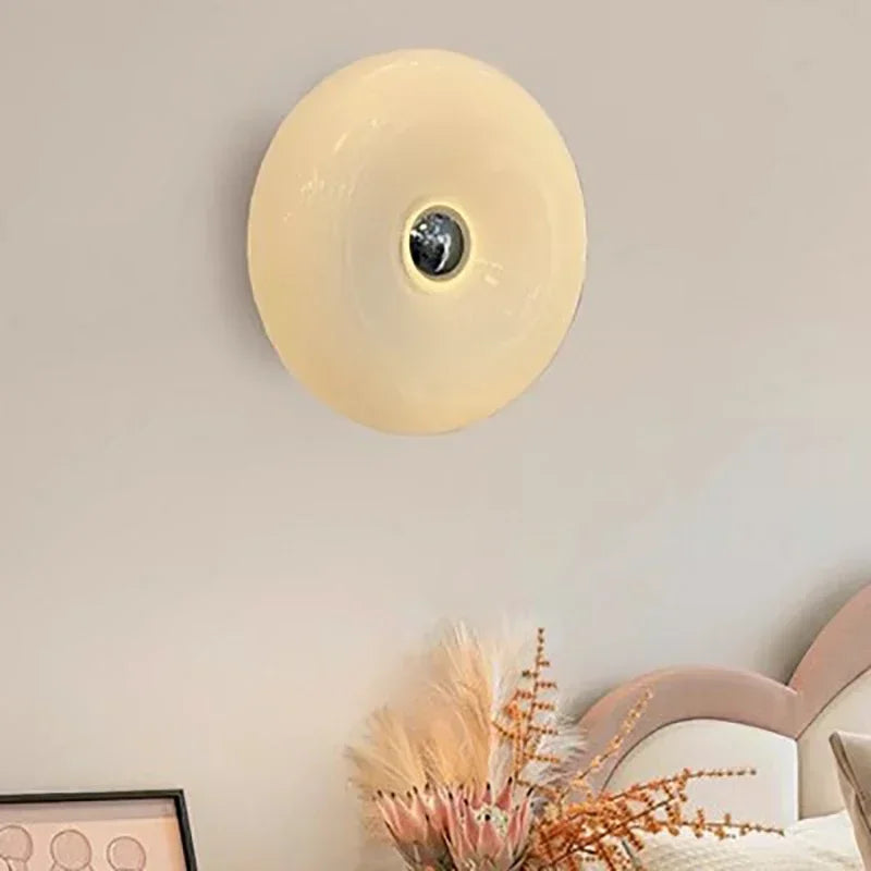 Round wall light fixture on a neutral wall with decorative elements below.