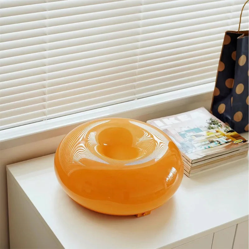 Orange round object on a surface with a window and magazine in the background