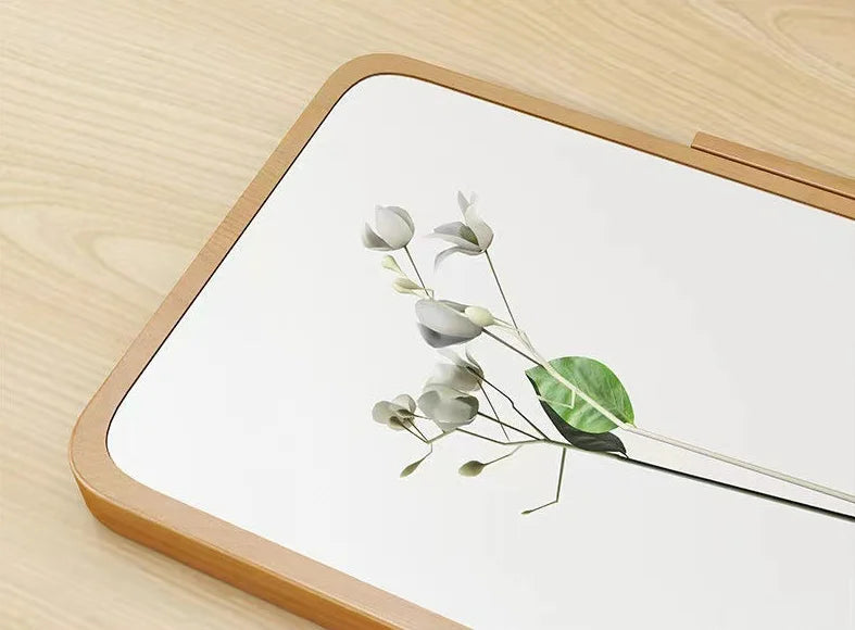 Mirror with a small white flower placed on top on a wooden surface