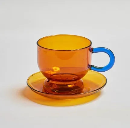 Amber glass cup and saucer with a blue handle on a white background