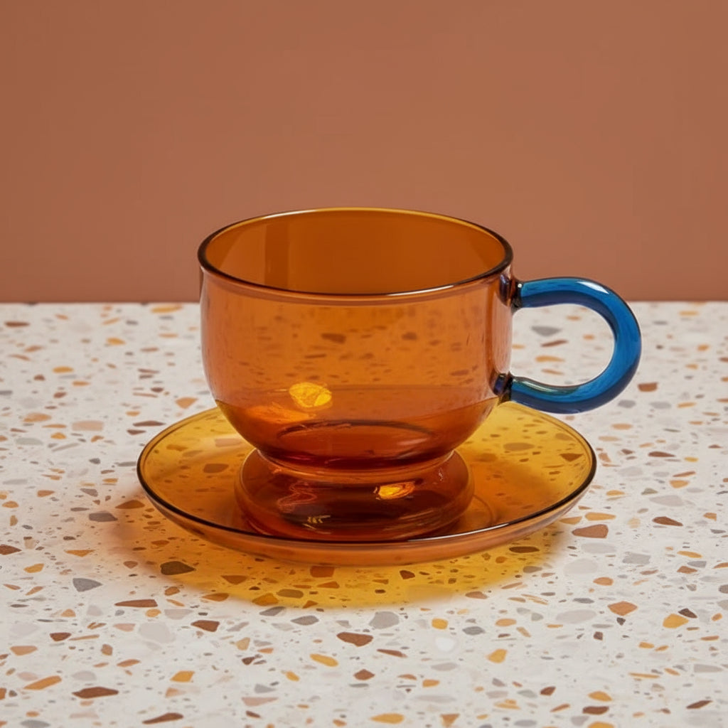 Amber glass cup and saucer with a blue handle on a white background