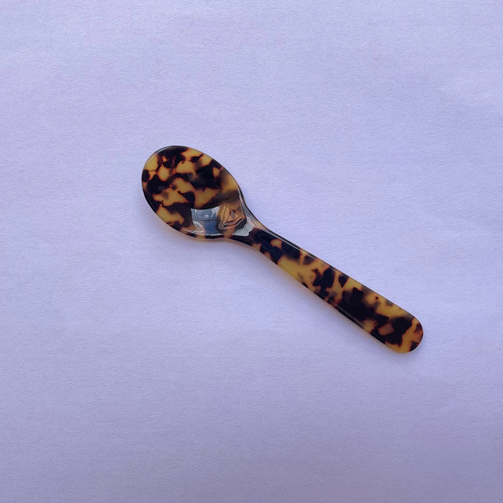 Tortoiseshell patterned spoon on a light purple background