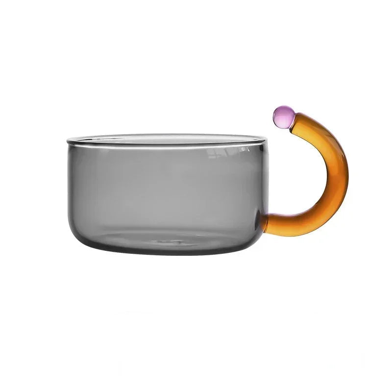 Glass mug with a multicolored handle on a white background