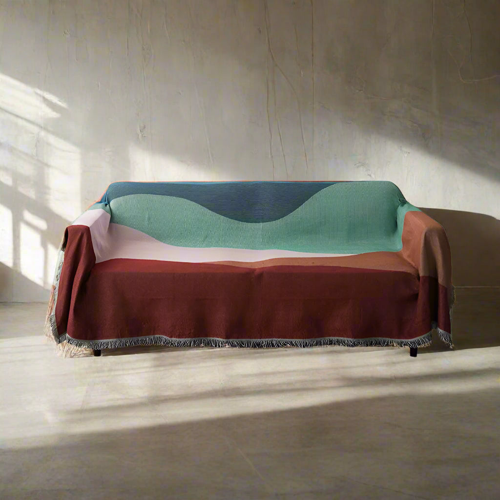 Multicolored blanket draped over a sofa on a white background
