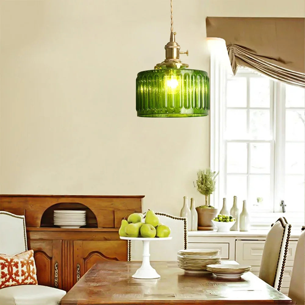 Dining room with a green pendant light, wooden table, and decorative elements.
