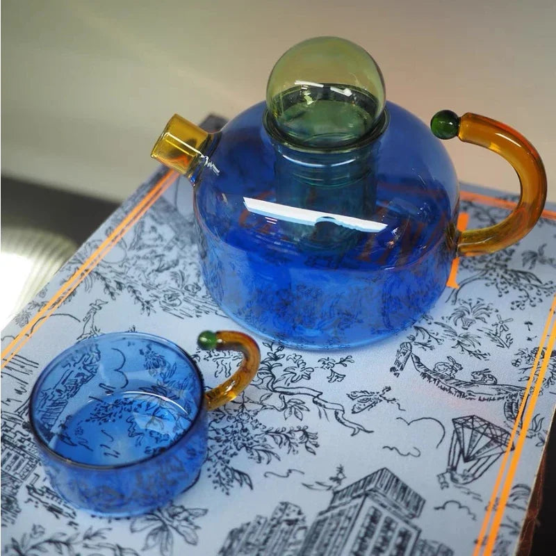 Blue glass teapot with amber handles on a decorative tray