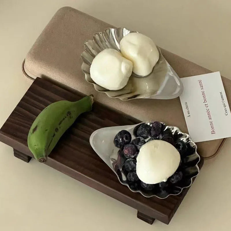 Two bowls with white spherical items and blueberries on a wooden tray with a beige background.