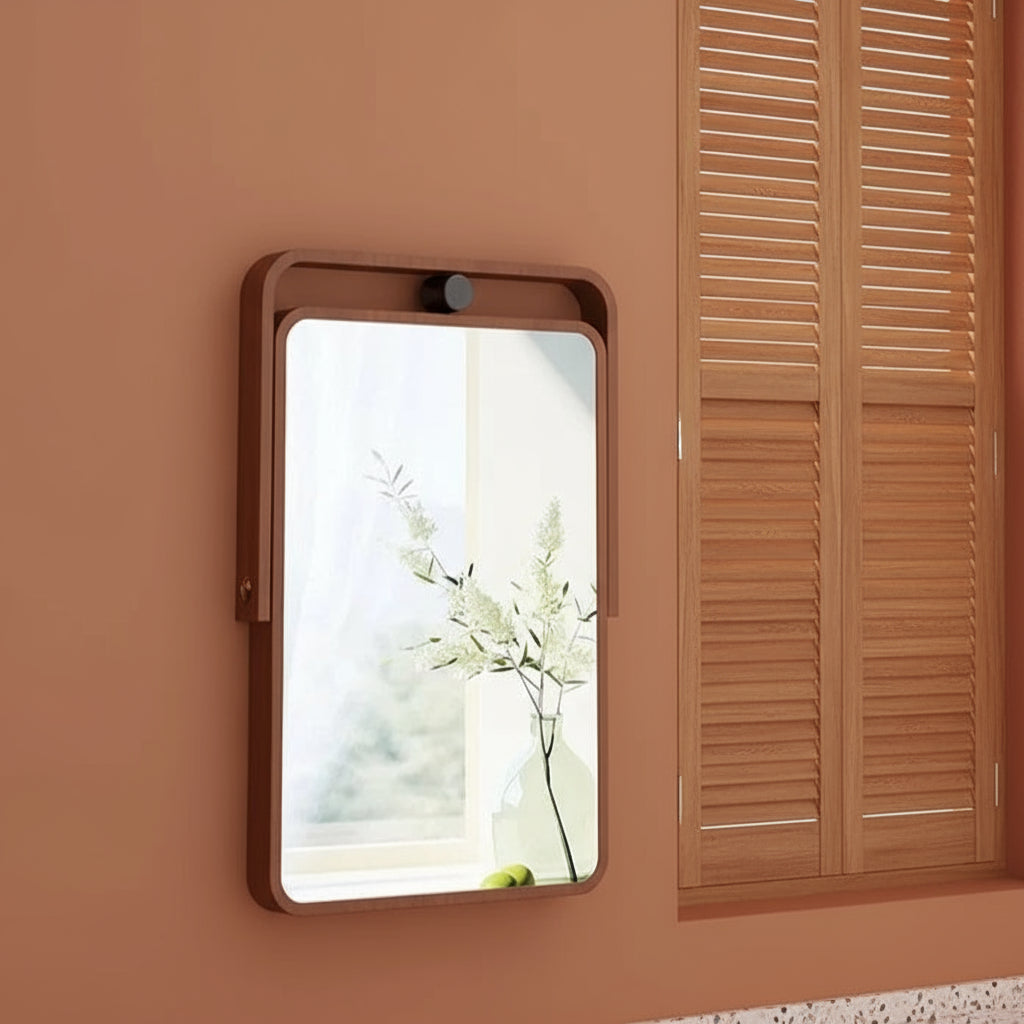 Rectangular mirror with wooden frame on a wall next to a window with blinds.