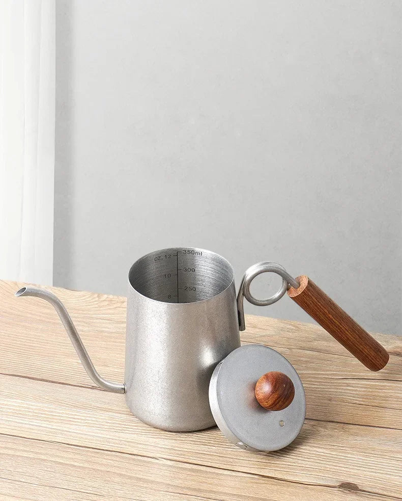 Stainless steel coffee pot with wooden handle and lid on a wooden surface