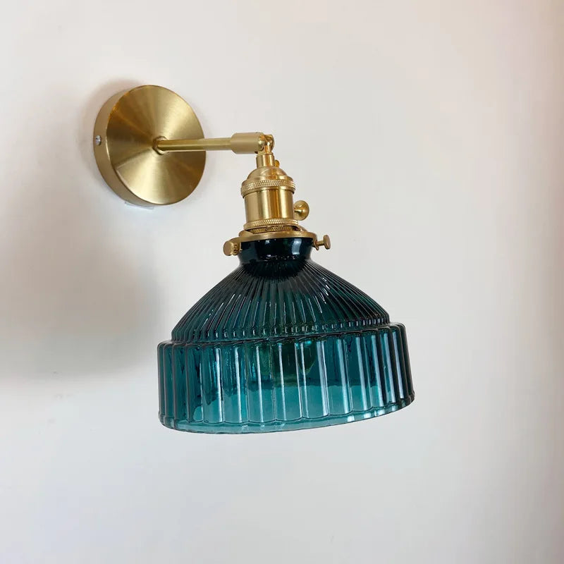 Wall-mounted lamp with brass fixture and blue glass shade on a white background