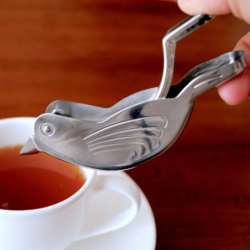 Metal tea infuser held over a cup of tea with a blurred background