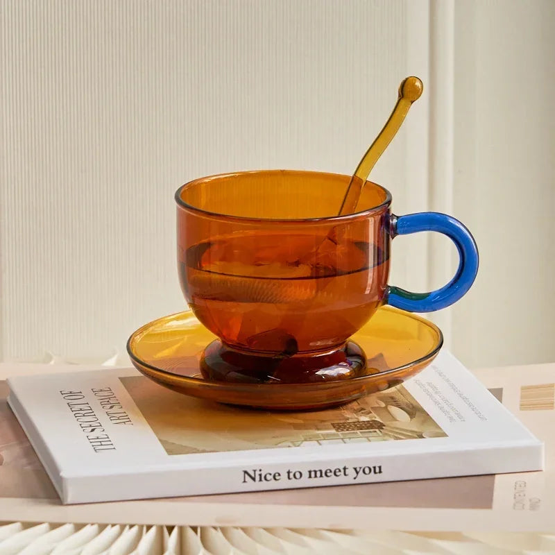 Amber glass cup with blue handle on a saucer, placed on a book with a neutral background