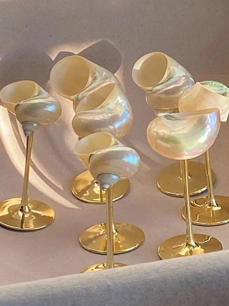 Set of decorative items with iridescent shells on gold stands against a neutral background
