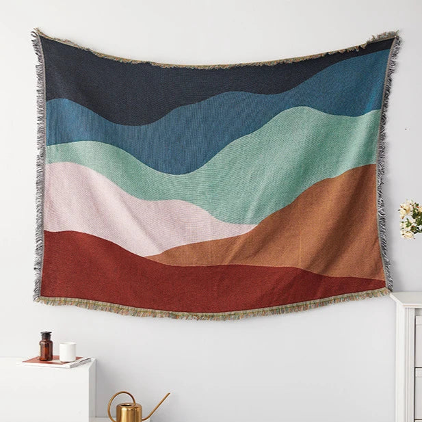 Colorful tapestry with wavy pattern hanging on a white wall.