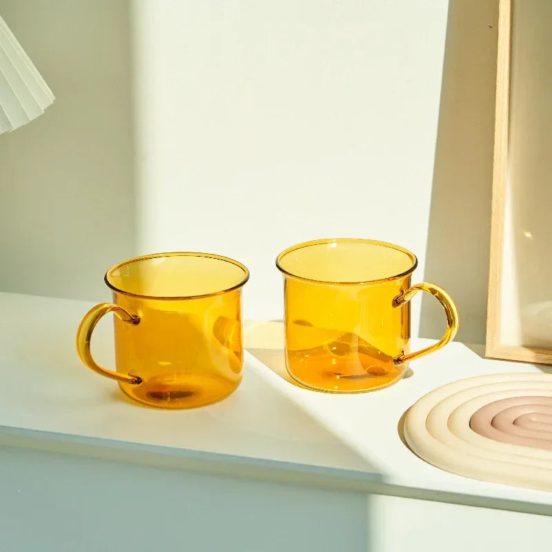 Two amber glass mugs on a white surface with a light background