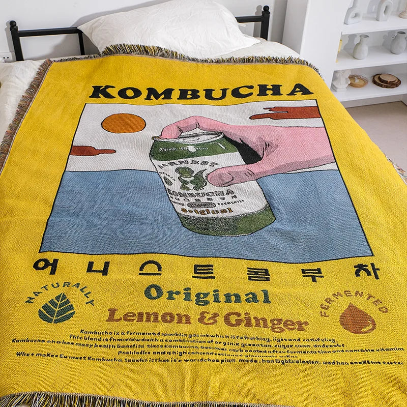 Blanket with kombucha design featuring a can and text on a yellow background