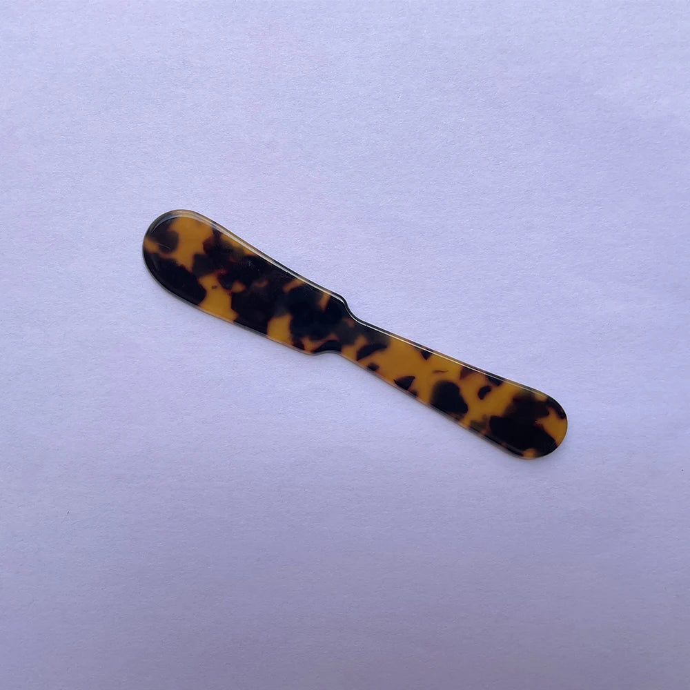 Butter knife with tortoiseshell pattern on a light purple background