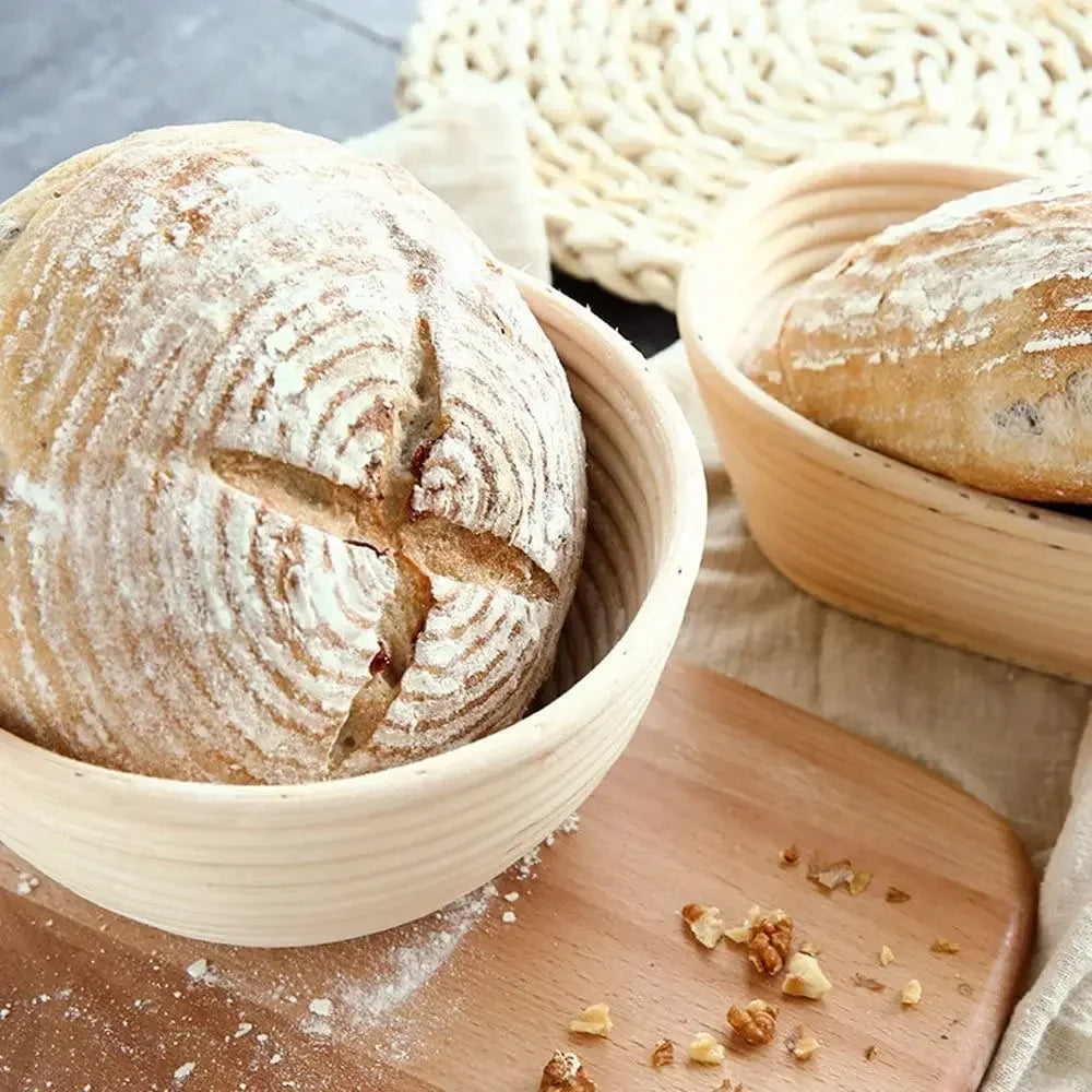 Loaves of bread in woven baskets on a wooden surface with flour and nuts.