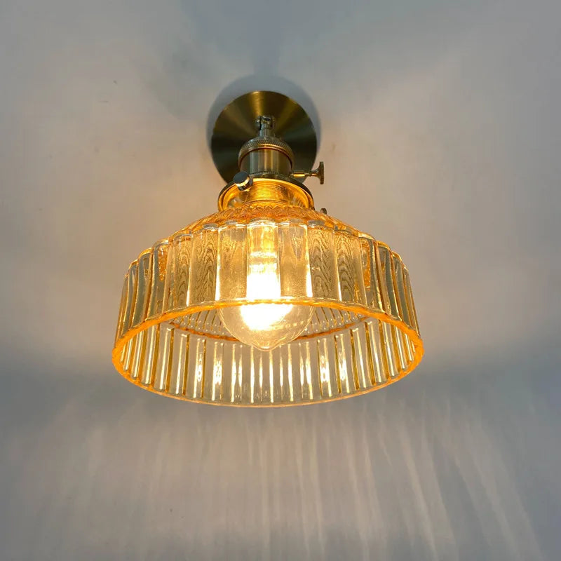 Ceiling light fixture with gold glass shade and brass fitting on a white ceiling.