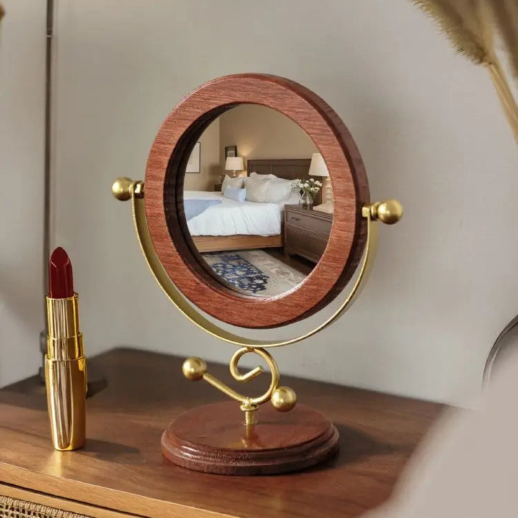 Wooden and gold vanity mirror on a dresser with a red lipstick next to it.