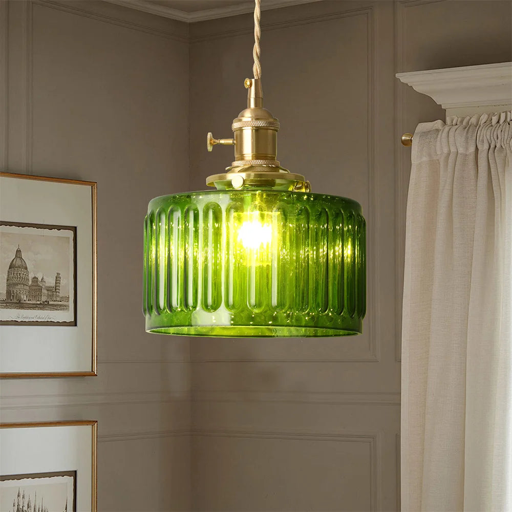 Green glass pendant light hanging in a room with framed pictures and a curtain.