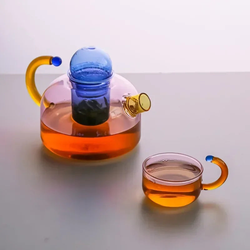 Glass teapot and cup with orange liquid on a white background