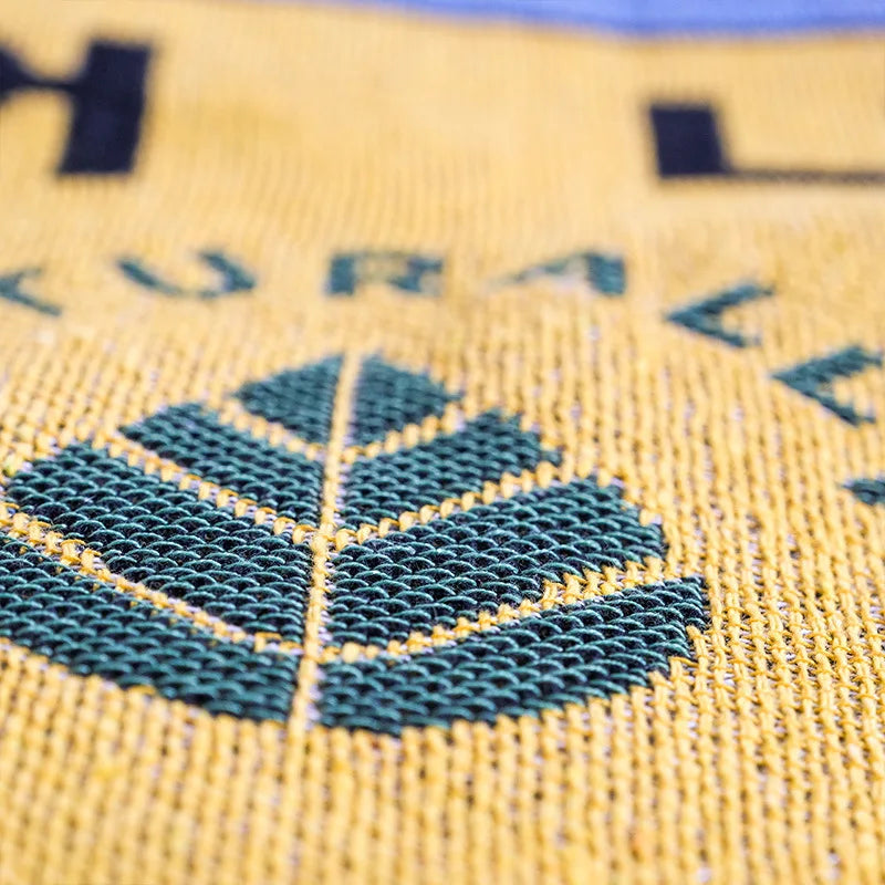 Close-up of a textured yellow surface with a green leaf design and partially visible text.