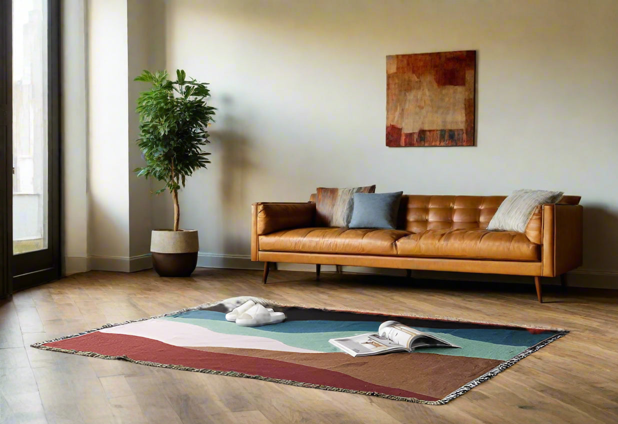 Gray sofa with decorative pillows on a colorful rug in a living room setting.