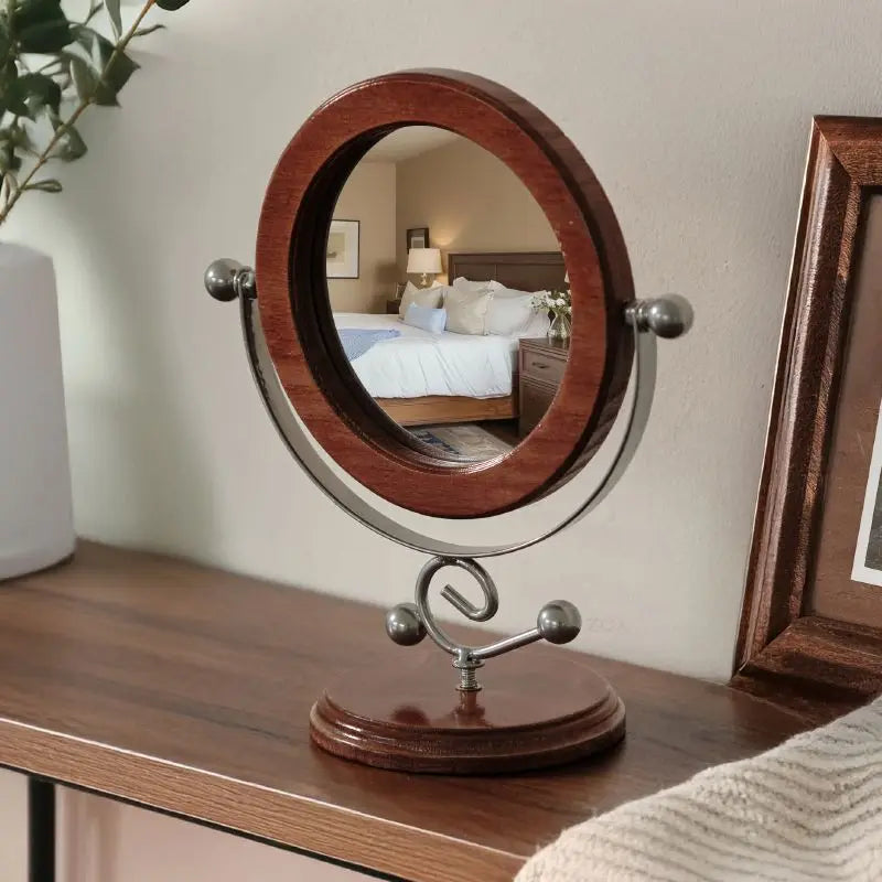 Round wooden-framed mirror on a stand with a bedroom reflection