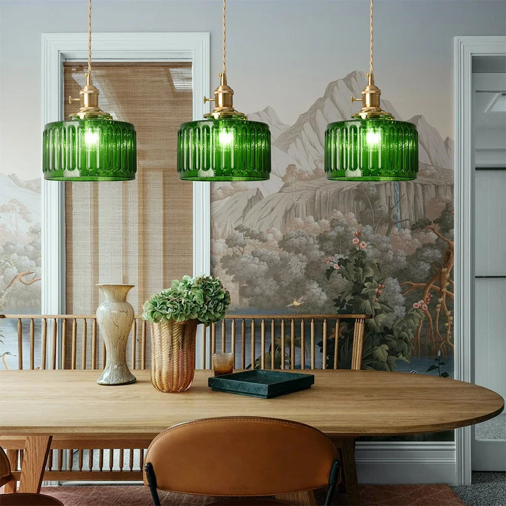 Green pendant lights hanging above a wooden table with decorative items.