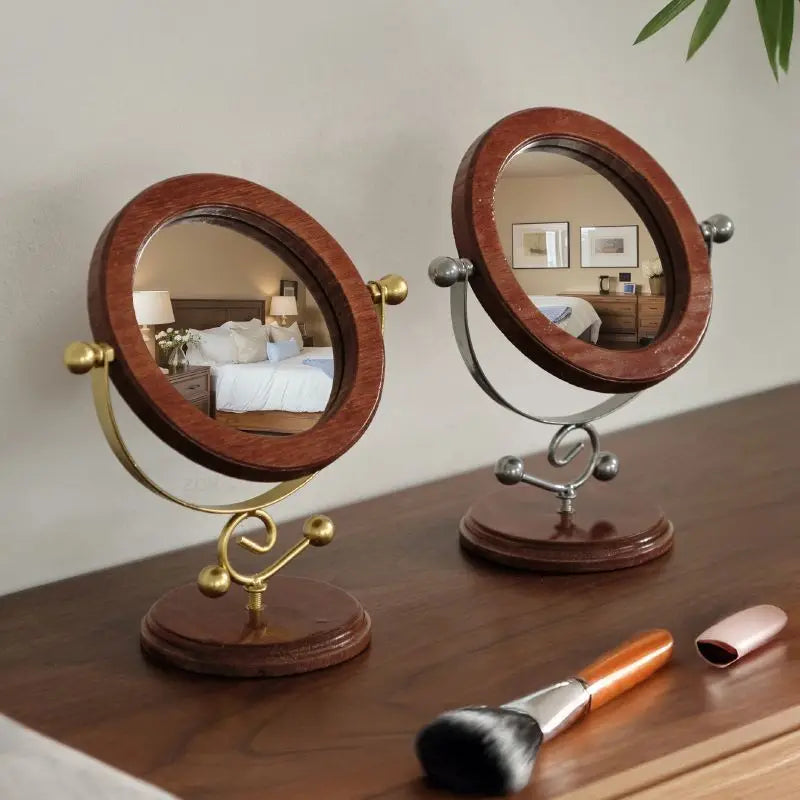 Two round mirrors on stands with a brush and lip gloss on a wooden surface.