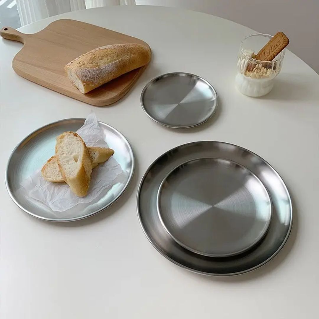 Stainless steel plates with bread on a white surface