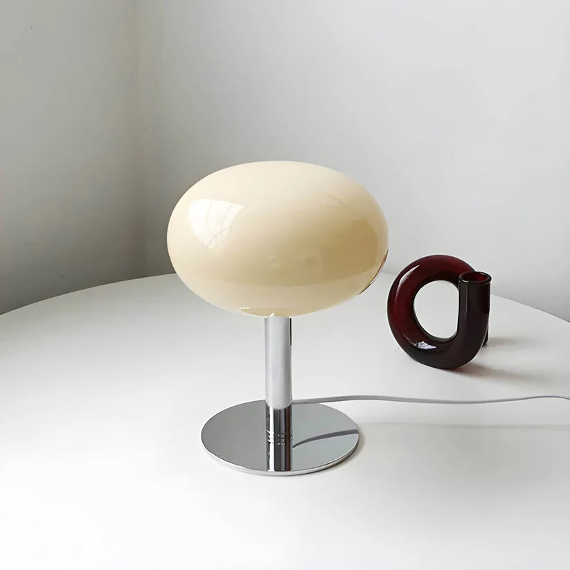 Modern table lamp with spherical beige shade on a white surface